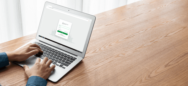 Hände tippen auf einer Laptop-Tastatur, auf dem Bildschirm ist die Website der Grundriss-Schmiede zu sehen.