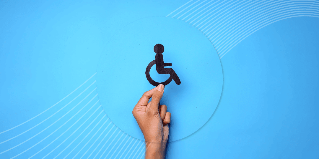 Hand hält ein dunkles Pappschild mit dem internationalen Rollstuhl-Symbol vor hellblauem Hintergrund mit grafischen Kreisbögen.