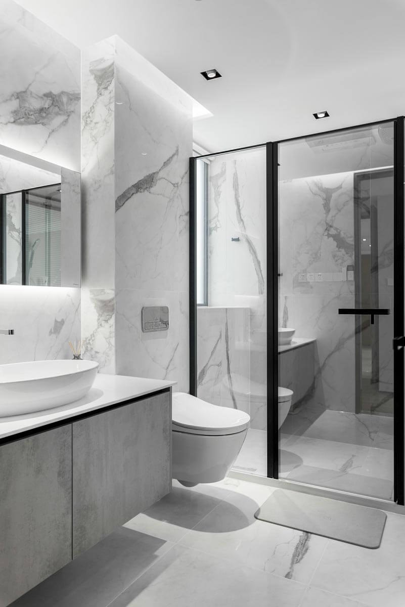 Modernes Badezimmer in Marmor und hellgrauem Holz mit begehbarer Dusche mit Glasumrandung, WC und hängendem Waschbeckenschrank.