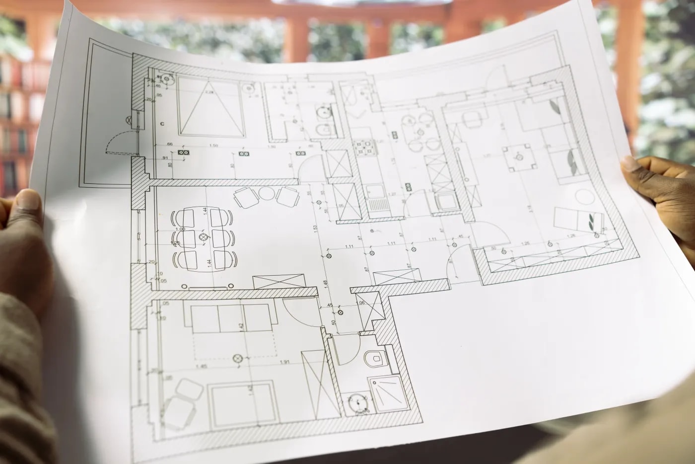 Eine Person hält den Bauplan einer 4-Zimmer Wohnung, die einen offenen Essbereich hat.