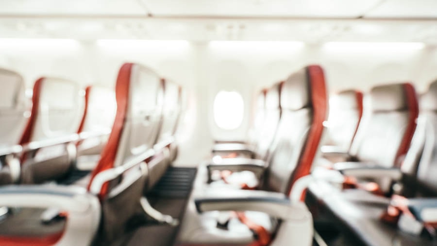 Verschwommene Aufnahme im innern eines Flugzeugs von typischen 3er-Sitz-Reihen.