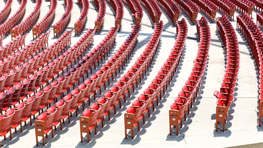 Aufsicht auf eine groößre Gruppe roter Klappsessel in einem riesigen Konzertsaal oder einer Arena.