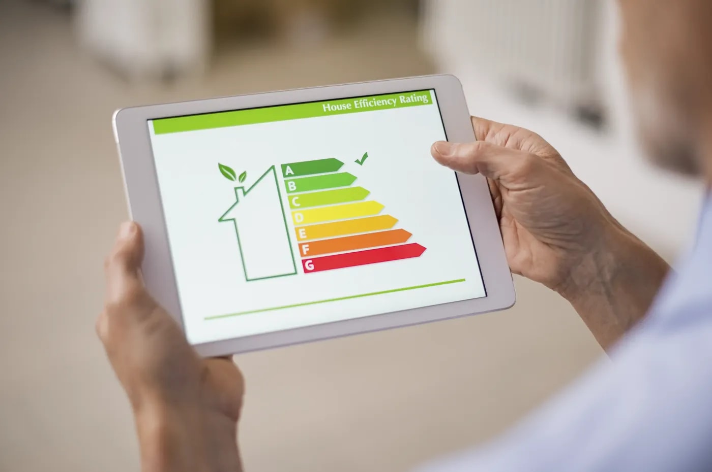Eine Person hält ein Tablet in den Händen, auf dem eine schematische Darstellung der Energie-Effizienz-Klassen zu sehen ist.