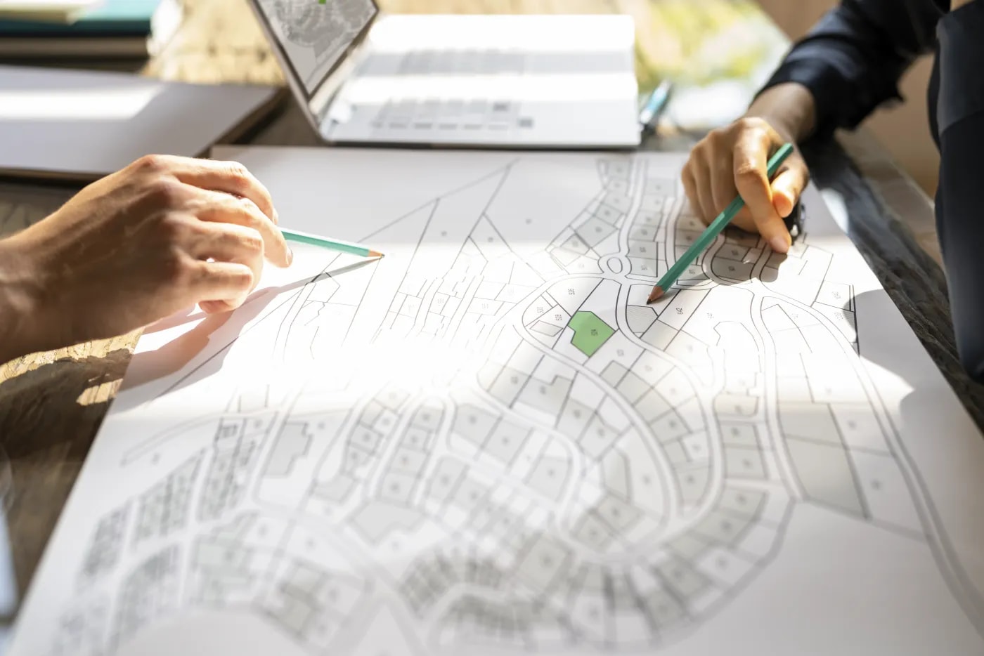 Zwei Personen sitzen an einem Flurplan und beraten über die Gegebenheiten der Lage unter Hinweisen auf verschiedene Details des Plans