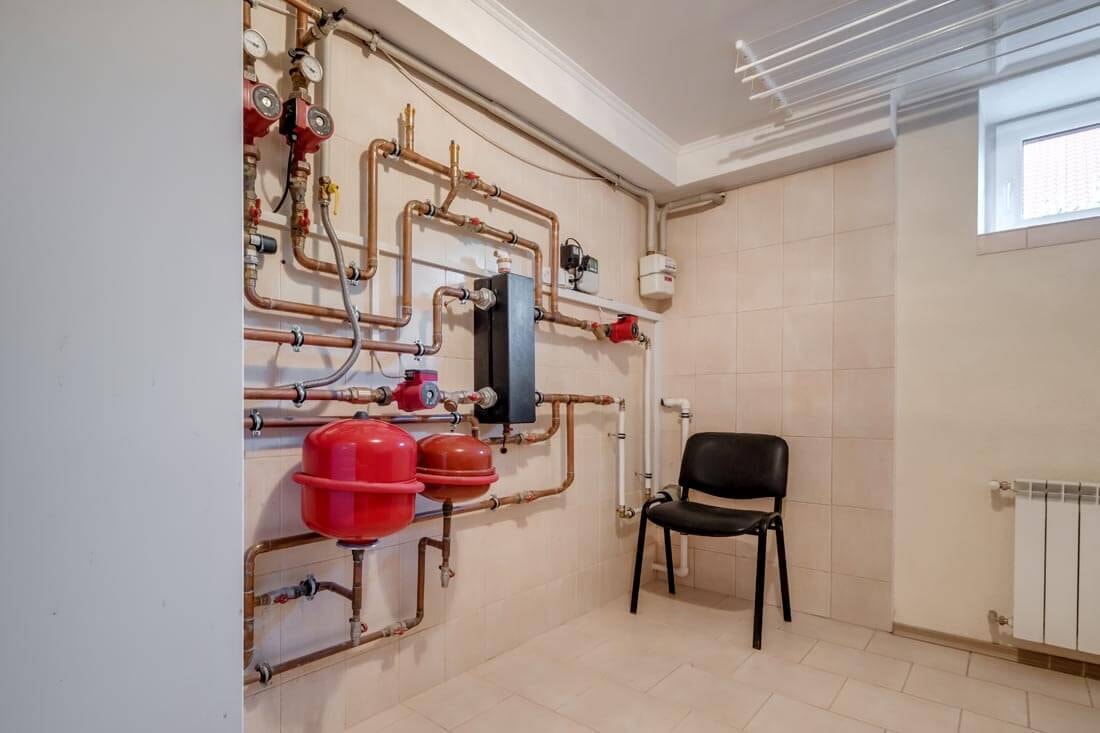 Aufnahme eines Kellerraums vom Eingang her, an dessen linker Wand sich einige Heizungsrohe befinden und in dessen hinterer Ecke ein Stuhl unter dem halben Fenster an der Oberseite der angrenzenden Wand.