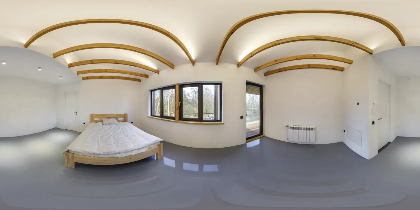 360 Grad Aufnahme eines hellen Raumes mit Deckenbalken und einem Holzbett, durch dessen Fenster ein Balkon und Gehölz zu sehen ist.