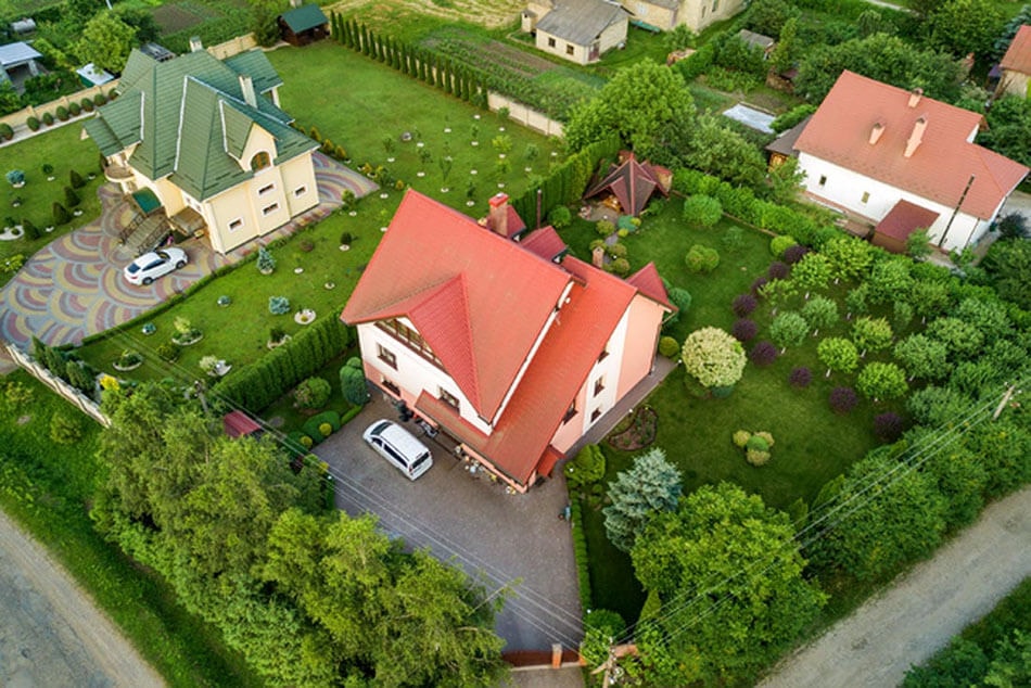 Foto von schräg oben auf ein mehrgeschossiges Mehrfamilienhaus mit üppiger Begrünung drum herum und zwei Nachbargebäuden in gehobener Optik.
