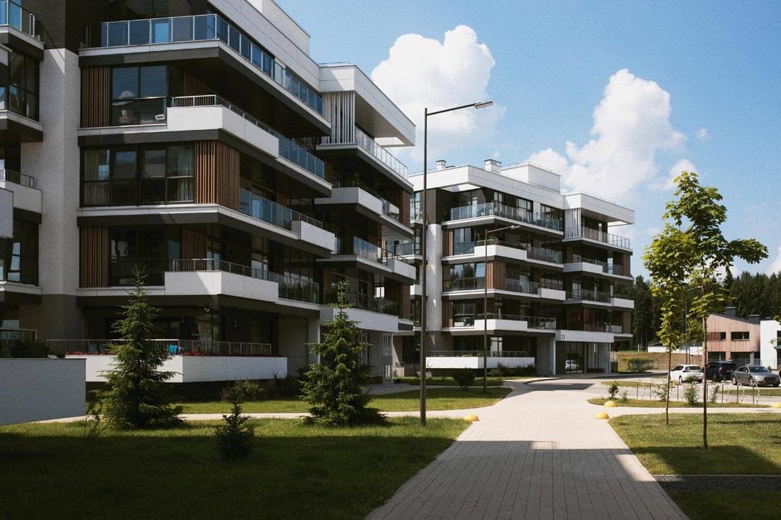 Sicht am Gehweg neben baugleichen modernen, hohen Mehrfamilienhäusern mit symmetrisch unterschiedlich gefassten Balkonen entlang.