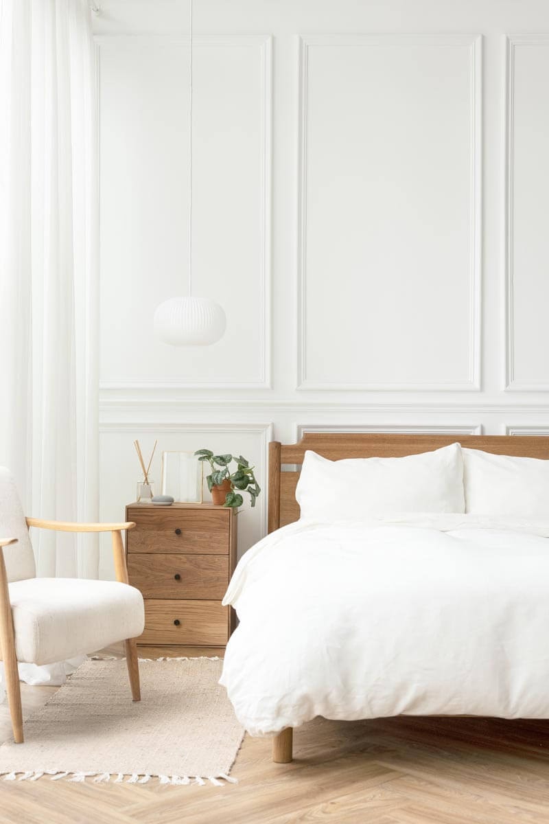 Helles Schlafzimmer im skandinavischen Stil mit weißer Wandtäfelung und Eichenholzmöbeln.